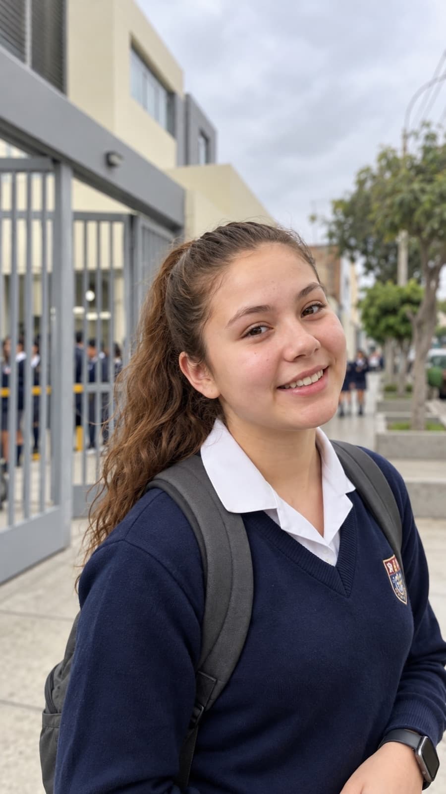 Una alumna sonríe al llegar a la puerta de su colegio.